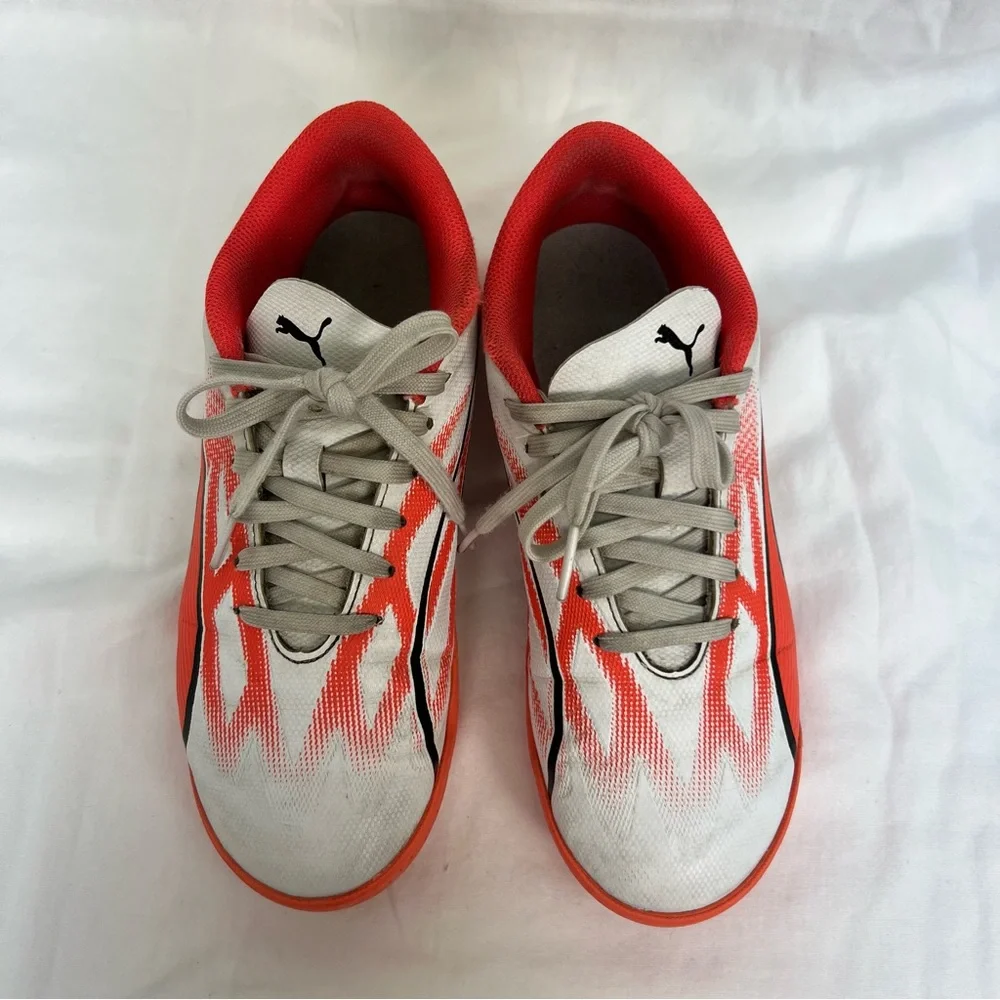Puma kids turf shoes in white, bright coral and black.